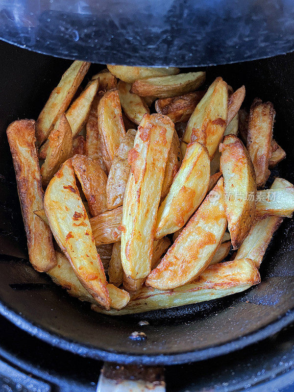 在空气炸锅里炸出的金黄色、新鲜酥脆的薯条/大块薯条，是零食烹饪的更健康的选择，从高处俯瞰